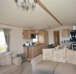 a living room with a sofa, kitchen area, and dining setup at Perran Sands - Holiday Accommodation 20514, Perranporth