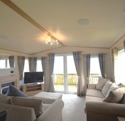 a living room with a television, sofa, and large windows at Perran Sands - Holiday Accommodation 20514, Perranporth