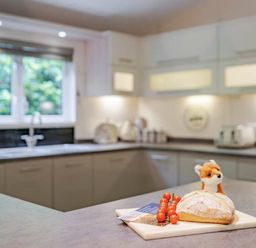 a kitchen with a loaf of bread and small tomatoes on a cutting board at Kelling Heath Holiday Park - Holiday Accommodation 20952 Weybourne