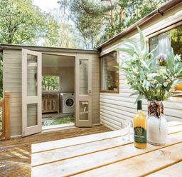 a porch with a beverage and vase near an open doorway at Kelling Heath Holiday Park - Holiday Accommodation 20958 Weybourne