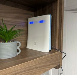 a white router on a wooden shelf next to a plant in a gray pot at Butlins Skegness - Holiday Accommodation 21028 Skegness