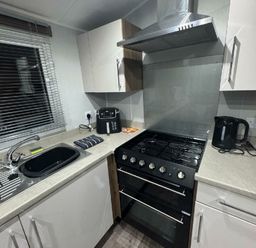 a kitchen with a gas stove, kettle, and sink at Butlins Skegness - Holiday Accommodation 21028 in Skegness