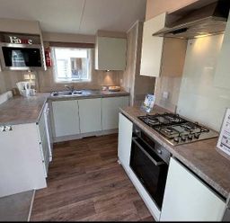 a kitchen with cabinets, a stove, and a sink at Perran Sands - Holiday Accommodation 21088 in Perranporth