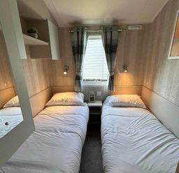 a bedroom with two single beds and a nightstand at Perran Sands - Holiday Accommodation 21088, Perranporth