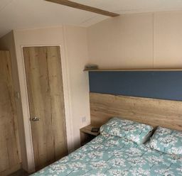 a bedroom with a bed and bedside table at Greenacres Holiday Park - Holiday Accommodation 21467 in Morfa Bychan