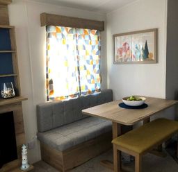 a dining area with a table and bench seating at Greenacres Holiday Park - Holiday Accommodation 21467, Morfa Bychan