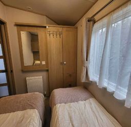 a bedroom with two single beds and a wooden wardrobe at Swanage Bay View - Holiday Accommodation 21567 in Swanage