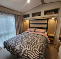 a bedroom with a bed featuring a patterned duvet and headboard at Swanage Bay View - Holiday Accommodation 21567 in Swanage