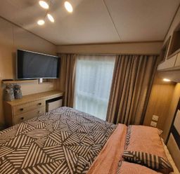 a bedroom with a bed and a television on the wall at Swanage Bay View - Holiday Accommodation 21567 in Swanage