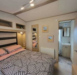 a bedroom with a bed, mirror, and door leading to a bathroom at Swanage Bay View - Holiday Accommodation 21567, Swanage