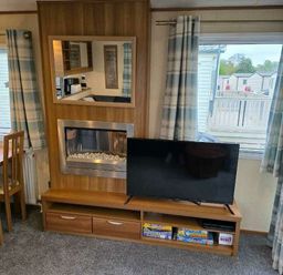 a living room with a wall-mounted TV, electric fireplace, and a mirror at Beacon Fell View Holiday Park - Holiday Accommodation 21653, Preston