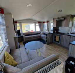 a living room with a sofa, coffee table, and kitchen area at Clarach Bay Holiday Village - Holiday Accommodation 21674 in Aberystwyth