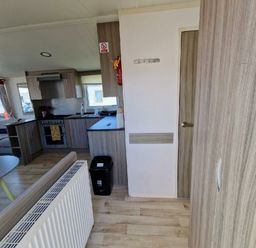 a kitchen area with cabinets, a stove, and a door leading to another room at Clarach Bay Holiday Village - Holiday Accommodation 21674, Aberystwyth