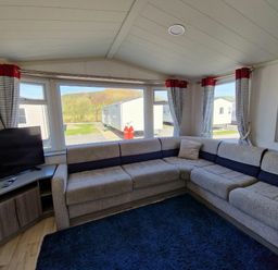 a living room with a corner sofa and a television at Clarach Bay Holiday Village - Holiday Accommodation 21674 in Aberystwyth