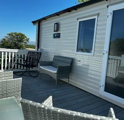a deck area with wicker furniture and a view at Brynowen Holiday Park - Holiday Accommodation 21677 Borth, Aberystwyth