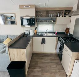 a kitchen with cabinets, a sink, microwave, and stove at Lido Beach Holiday Park - Holiday Accommodation 21682, Prestatyn
