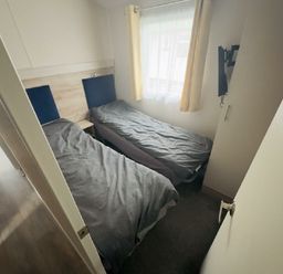 a bedroom with two single beds covered with gray bedding at Lido Beach Holiday Park - Holiday Accommodation 21682, Prestatyn