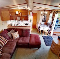 a living room area with a sectional sofa and dining table at Hafan y Mor Haven - Holiday Accommodation 21715 Pwllheli