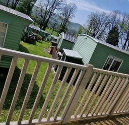 a view of several green cabins in a grassy area at Woodlands Holiday Park - Holiday Accommodation 21859 in Twywn