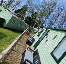 a row of holiday cabins with a walkway and outdoor seating at Woodlands Holiday Park - Holiday Accommodation 21859 in Twywn