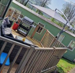 a deck area with a grill and seating located at Woodlands Holiday Park - Holiday Accommodation 21859 in Twywn
