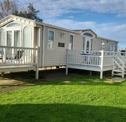 a mobile home with a deck and grass area at Butlins Skegness - Holiday Accommodation 22071 in Ingoldmells