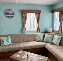 a seating area with a brown couch and decorative cushions at Valley Farm Holiday Park - Holiday Accommodation 22153 Clacton-on-Sea