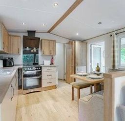 a kitchen area with wooden cabinetry and a dining table at Kelling Heath Holiday Park - Holiday Accommodation 22244, Holt