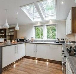 a kitchen with skylights, modern cabinets, and a countertop at Kelling Heath Holiday Park - Holiday Accommodation 22249, Holt