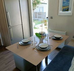 a dining table set with plates and glasses at Lyons Winkups and Primrose - Holiday Accommodation 22330 in Towyn