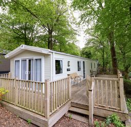 A static caravan with decking and chairs at 145 Woodside View Porthmadog