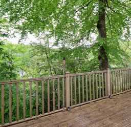 A wooden deck area surrounded by trees at 145 Woodside View in Porthmadog