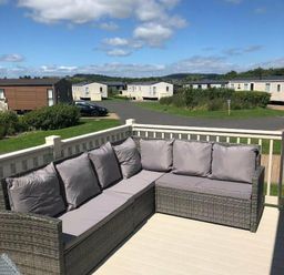 a patio area with a sectional sofa overlooking a holiday park at Lakeland Leisure Park - Holiday Accommodation 3166 Flookburgh