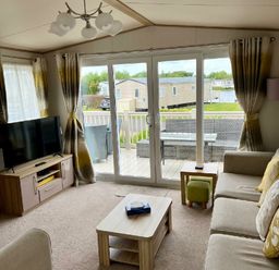 a living room with a TV and sliding glass doors leading to a deck at Lakeland Leisure Park - Holiday Accommodation 3166 Flookburgh