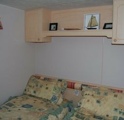 a bedroom with two beds and shelves containing photos at Edwards Leisure Park - Holiday Accommodation 318, Towyn