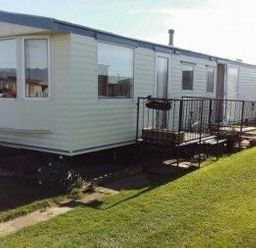 a mobile home with a front deck on grass at Edwards Leisure Park - Holiday Accommodation 318 Towyn