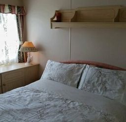 a bedroom with a double bed and a lamp on a bedside table at Edwards Leisure Park - Holiday Accommodation 318 Towyn