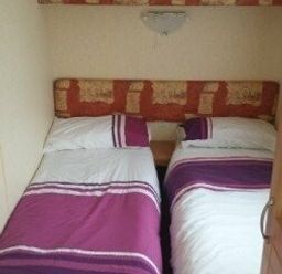 a bedroom with two twin beds and a headboard at Seven Bays Park (Maribou) - Holiday Accommodation 3966, St Merryn