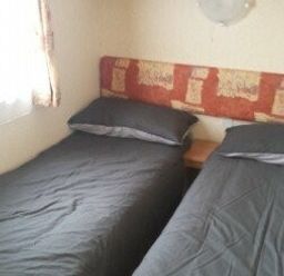 a bedroom with two single beds and a bedside table at Seven Bays Park (Maribou) - Holiday Accommodation 3966, St Merryn