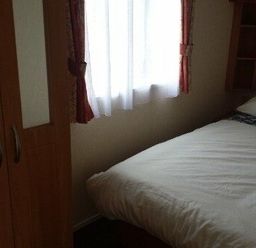 a bedroom with a bed and a wardrobe at Seven Bays Park (Maribou) - Holiday Accommodation 3966 St Merryn