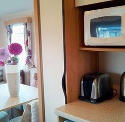 a kitchen area with a toaster and microwave on shelves at Swanage Bay View - Holiday Accommodation 464 in Swanage