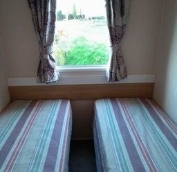 a bedroom with two single beds and a window with curtains at Swanage Bay View - Holiday Accommodation 464 in Swanage