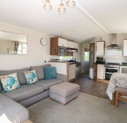 A living room with a sofa, dining table, and kitchen area at Hopton Holiday Village - Holiday Accommodation 632, Hopton-On-Sea