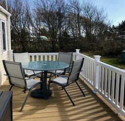 a dining table with chairs on a deck at Greenacres Holiday Park - Holiday Accommodation 6757 in Porthmadog