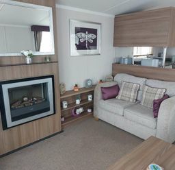 a living room with a fireplace and sofa at Reighton Sands Holiday Park - Holiday Accommodation 6837, Filey