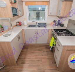 a kitchenette with cabinets, sink, stove, and appliances at Devon Cliffs Holiday Park - Holiday Accommodation 6955 in Exmouth