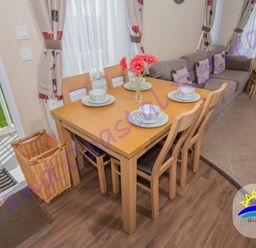 a dining table set with plates and flowers next to a sofa at Grand Coastal Retreats