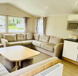 a living room with a sectional sofa and a table at Hafan y Mor Haven - Holiday Accommodation 7421 Pwllheli