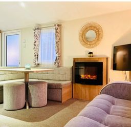 a seating area with a round table and a fireplace at Hafan y Mor Haven - Holiday Accommodation 7421 Pwllheli