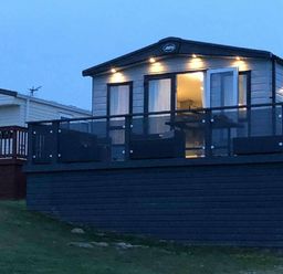 a lodge with a balcony and outdoor seating area at Perran Sands - Holiday Accommodation 7528, Perranporth, Cornwall, United Kingdom